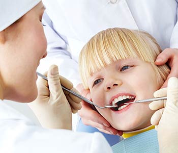 Pediatric dentist examining teeth of girl